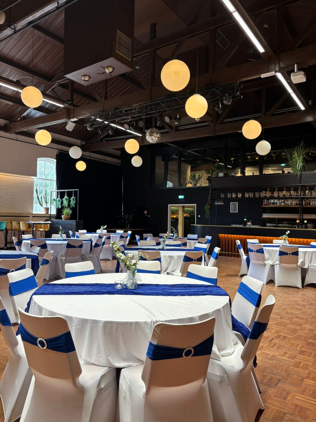Feestzaal aangekleed in koningsblauw met bloemstukken