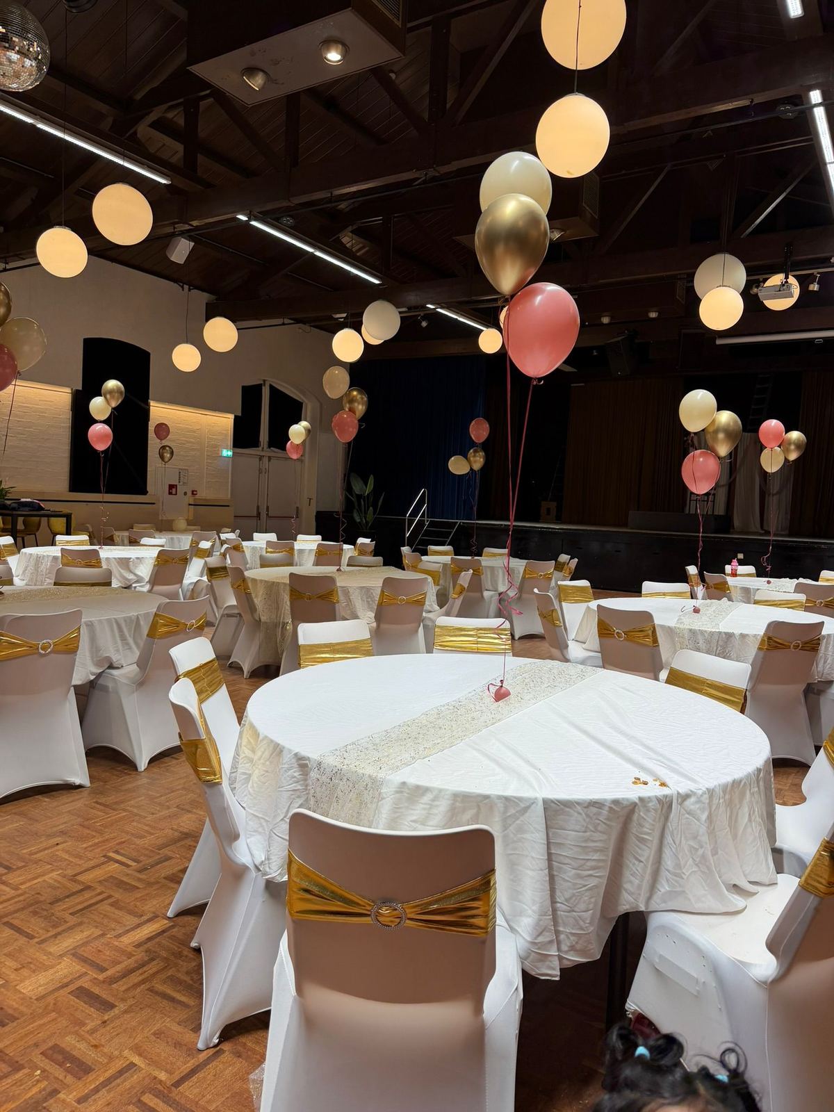 Feestzaal aangekleed in goud en roze met heliumballonnen
